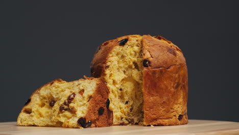 traditional english christmas cake tied with a jute thread on the black background. italian classic panettone .pastry chef sprinkles powdered sugar through a sieve on the fruit easter cake with raisins. high quality 4k footage