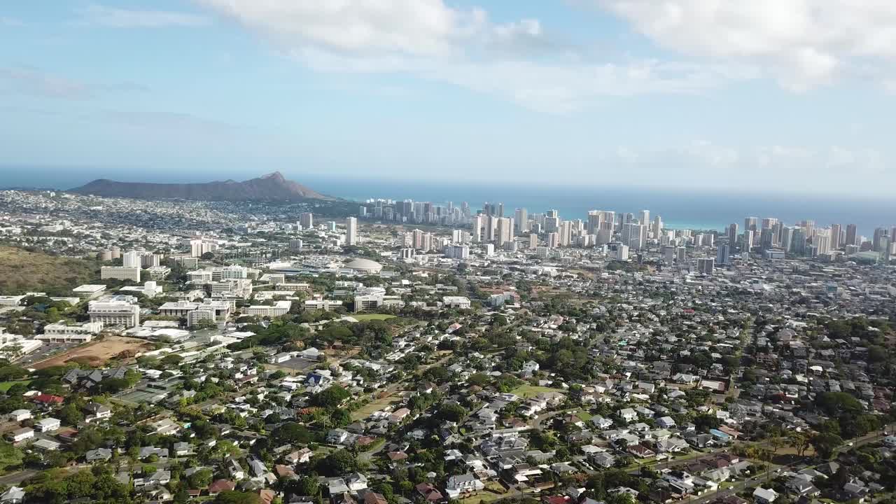 Cityscape or Waikiki district in Honolulu, on Hawaii island. Aerial wide shot. Sunny summer day with dense houses and homes. Peaceful suburb with downtown skyline in distance