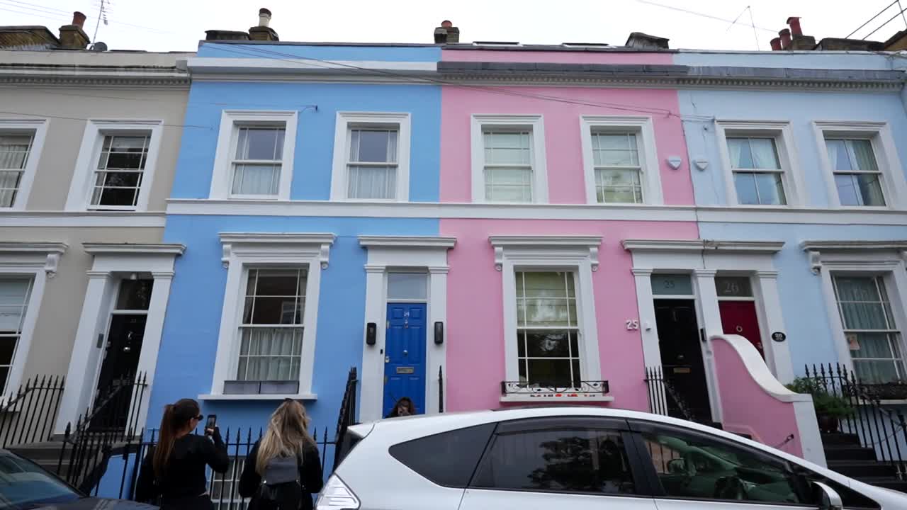 Tourists take selfies in front of some typical colorful houses in Notting Hill, London