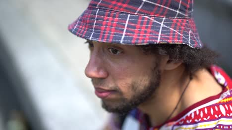 an ethnic young man looking around while dressed in urban street clothing.