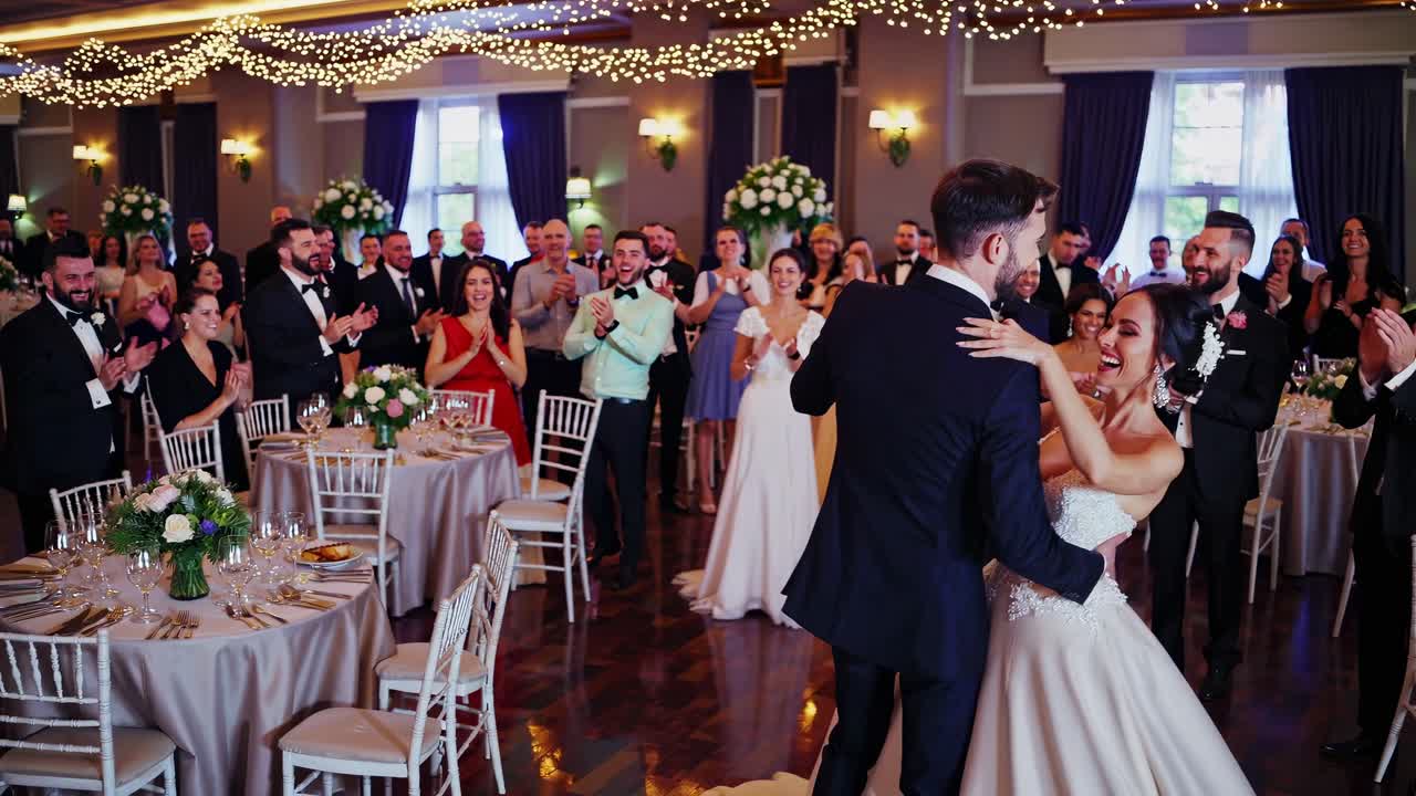 Imagem em grande angular de uma elegante recepção de casamento, capturando convidados em trajes formais celebrando.