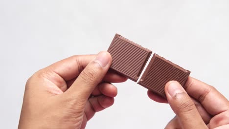 hands holding a broken chocolate bar