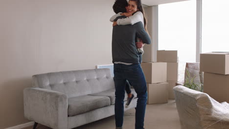 young couple moving house new home owners smiling enjoying successful move hugging in apartment