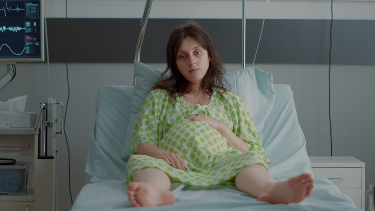 Portrait of pregnant person sitting in hospital ward bed