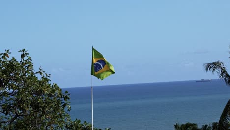 brazil flag close-up waving in the wind in 120fps slow motion with the vast ocean in the background in the historic city of olinda in pernambuco, brazil