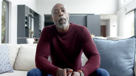 Portrait-of-happy-biracial-man-sitting-on-couch-and-having-video-call-at-home,-slow-motion