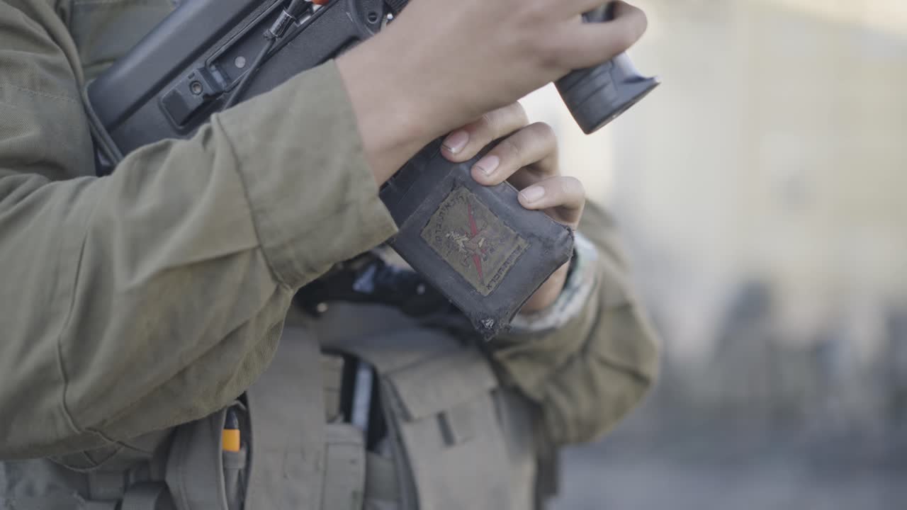 Close up of Israeli soldier's hand unfastening the magazine from his rifle