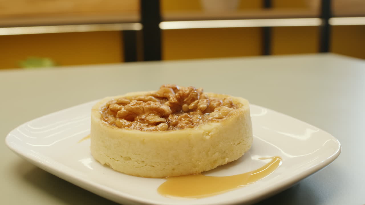 Panning shot of a cheesecake garnished with whole walnuts on top, highlighting its creamy texture and crunch