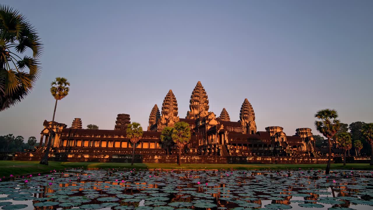 Wide-angle shot of Angkor Wat at sunrise, capturing the temple's grandeur and reflection in a lotus