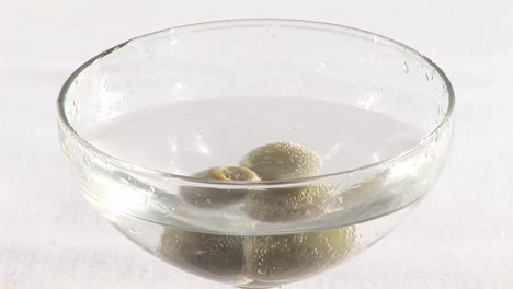 olives falling into a martini glass