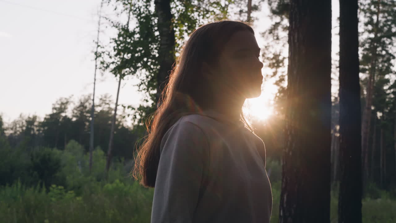 Donna triste passeggia nel bosco al tramonto. Una giovane donna riposa in una fitta foresta pensando da sola al significato della vita. Sensazione di vuoto e solitudine.