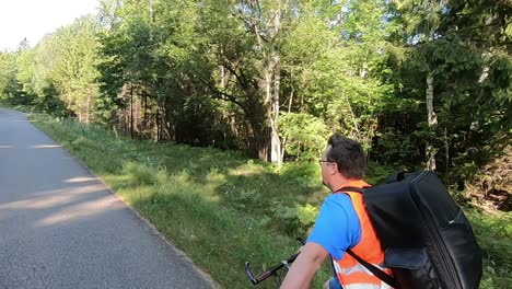 A-cyclist-with-orange-vest-and-backpack-rides-a-bike