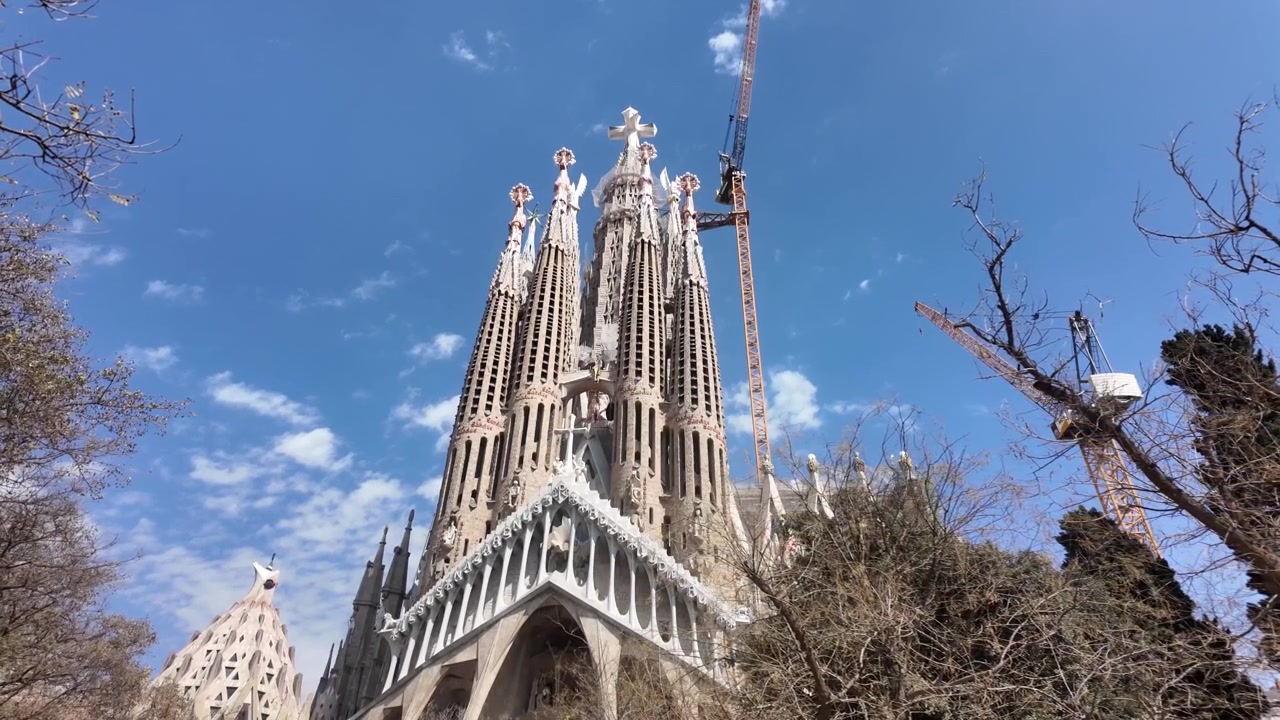 Ampia vista della facciata della Sagrada Familia con gru che mostrano la costruzione in corso a Barcellona.