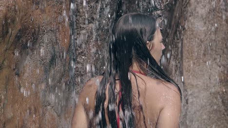 slim girl in bright red swimsuit touches long dark hair