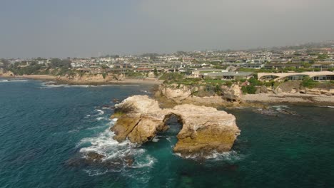 Tiro-De-Drone-De-Una-Enorme-Formación-Rocosa-Frente-A-La-Playa-De-Newport,-Ca