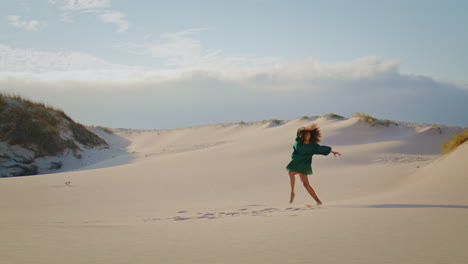 artista morena bailando dunas de arena en verano. mujer moviéndose activamente en el desierto.