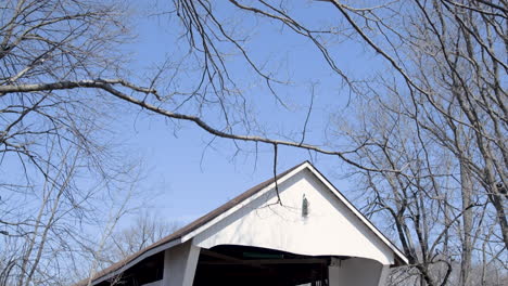 Exterior-of-Old-Wooden-Covered-Bridge-Panning-Down-from-Sky