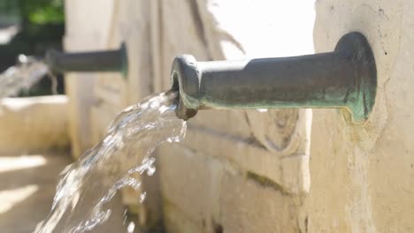 Close-up-of-running-water-from-an-old-tap-during-a-sunny-day