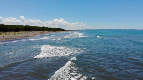 Sea-waves-foaming-and-splashing-on-sandy-beach-with-no-people-near-pine-trees-forest-in-Adriatic-seaside-of-Albania