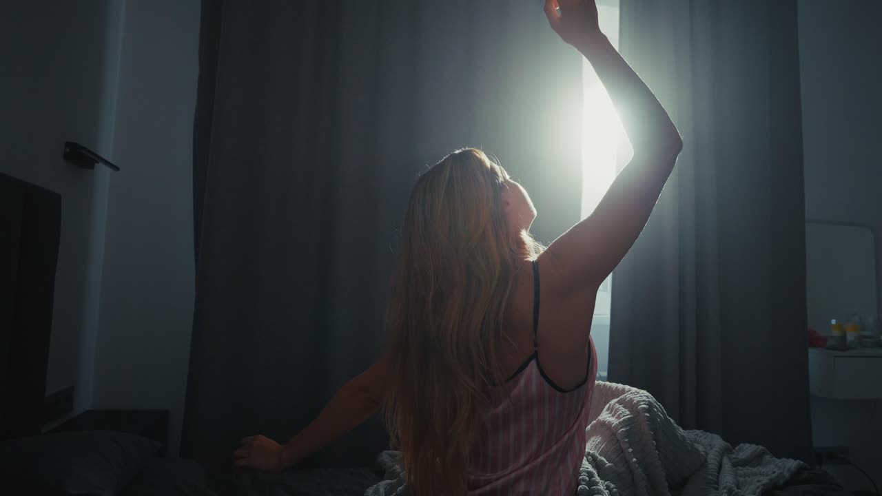 Woman waking up in bed, enjoying morning light