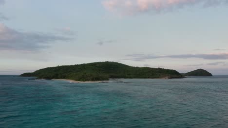 Stunning-scenery-of-tropical-island-in-frame-captured-by-drone-hanging-static-above-ocean-water-during-sundown