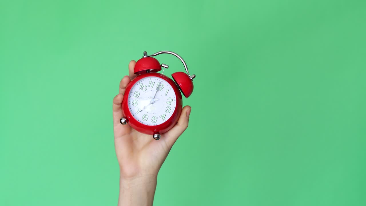크로마 키 배경에 알람 시계를 들고 있는 여자 손