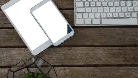 video de tableta y teléfono inteligente con pantallas en blanco y teclado sobre fondo de madera