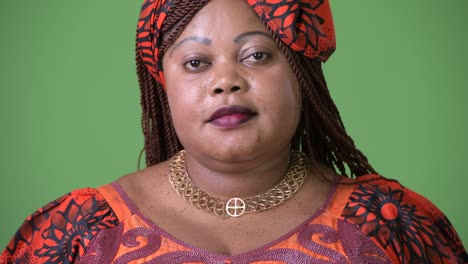 una hermosa mujer africana con sobrepeso que lleva ropa tradicional contra un fondo verde