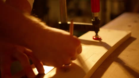 Close-up-of-a-carpenter-marking-with-lines-the-measurements-on-a-wooden-board-to-cut-it