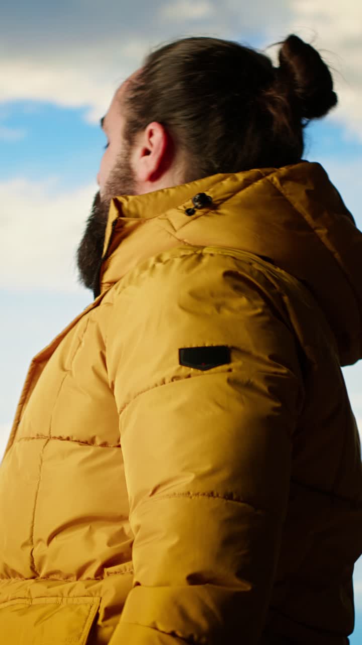 Man in Yellow Puffer Jacket Looking Up at Mountain Landscape