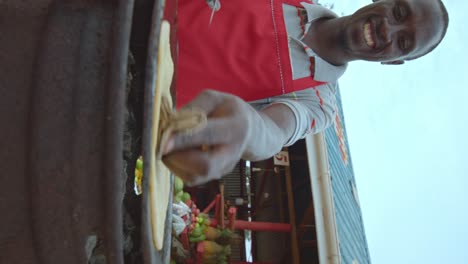 happy vendor cooking traditional chapati flatbread in the street of kampala in uganda