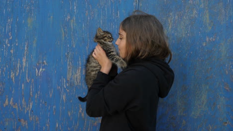 teenager repeatedly kisses small fluffy cat