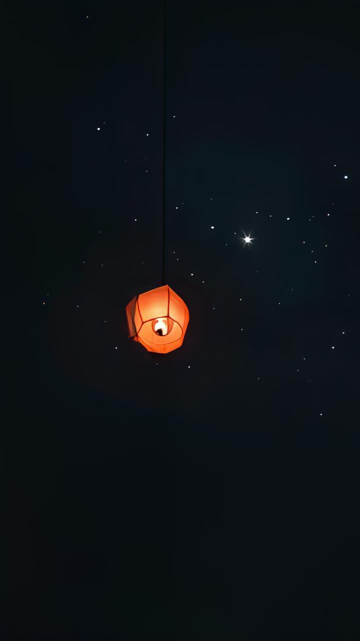 Vertical video: Camera zooming closer to hanging orange lantern at night, revealing bulb and sparks
