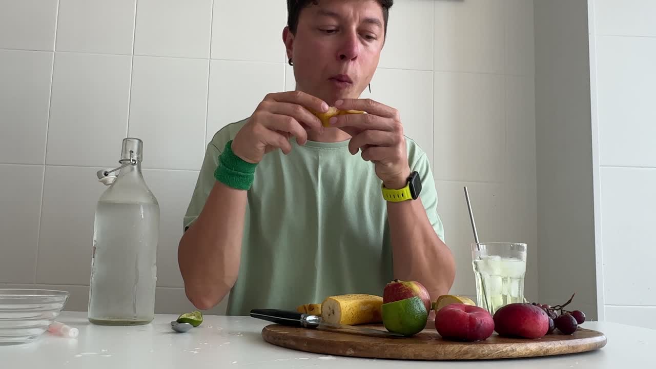 Uomo che si gode uno spuntino di frutta sano in cucina.