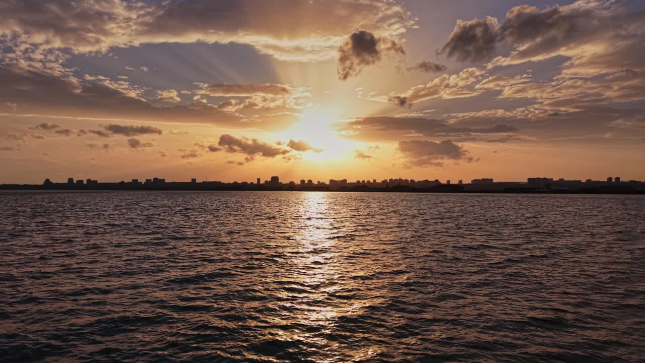 Sunset over city skyline by water during evening hours