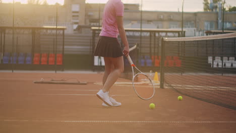 Una-Joven-Está-Cansada-Después-De-Un-Intenso-Entrenamiento-De-Tenis-Al-Aire-Libre.-Hace-Rodar-Pelotas-De-Tenis-A-Lo-Largo-De-La-Red.