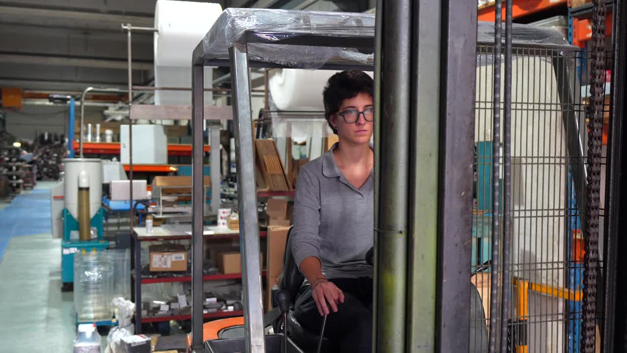 Donna che guida un carrello elevatore in una fabbrica