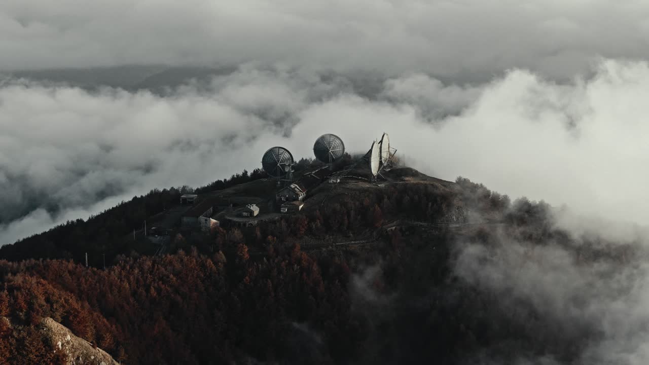 Remote Satellite Station on a Mountain Peak in Thick Clouds