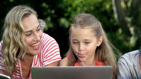 Portrait-of-cute-family-are-lying-on-the-grass-and-using-electronic-devices