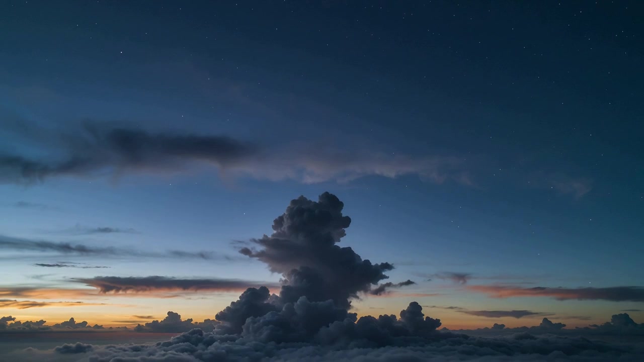 Stigende cumulus-skyer, der bliver mørkere over skydækket set fra fly, mens solnedgangen aftager og afslører skær og stjerner
