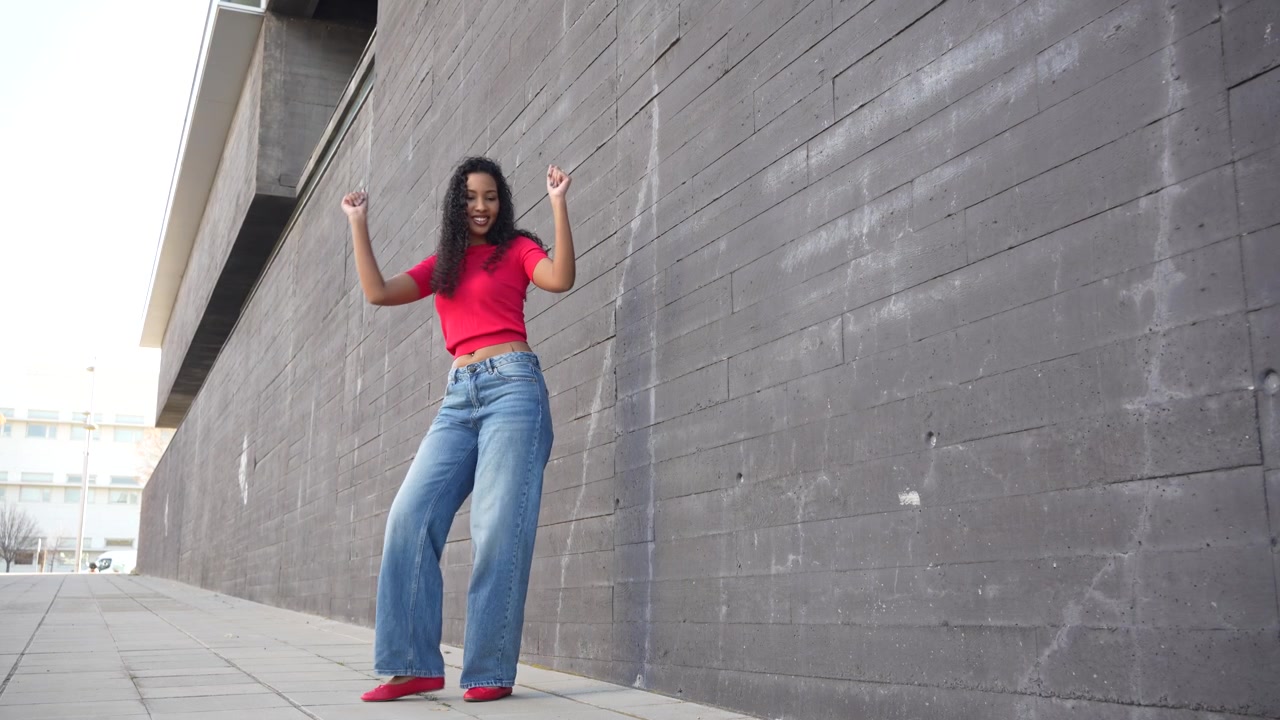 Una giovane donna elegante posa in un ambiente urbano mentre indossa un outfit casual.