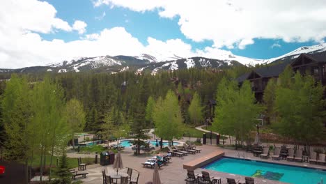 wide tilting up shot from resort pool to the rocky mountain peaks in the summer