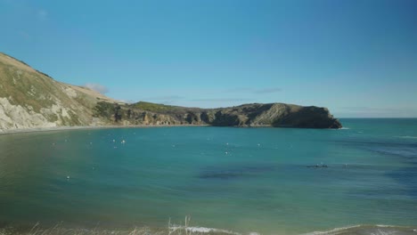 toma de paisaje cinematográfico de 4k de la playa de lulworth cove, dorset en un día soleado