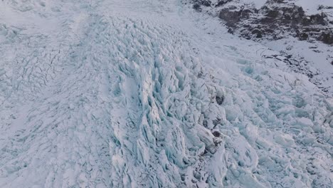 aerial view over irregular ice formations in falljokull glacier covered in snow, iceland