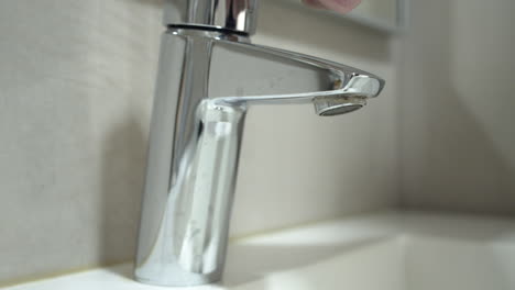 man opening the tap and washing his hands only with water