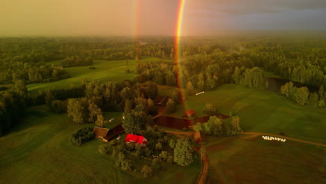 a double rainbow over a countryside farm in a green landscape - aerial view