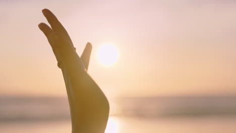 Cerrar-La-Mano-De-Una-Mujer-Alcanzando-La-Luz-Del-Sol-En-La-Playa-Jugando-Con-Rayos-Dorados-Al-Atardecer