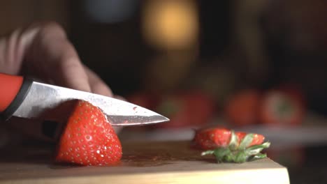 woman hands cutting red strawberries on wooden board using a sharp knife