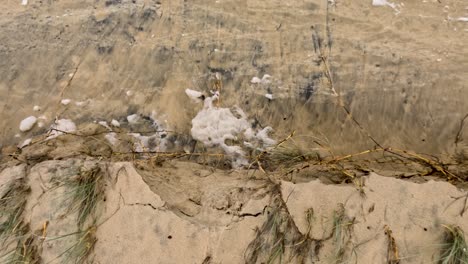 las olas chocan contra una orilla arenosa, ilustrando la erosión y la contaminación durante el ciclón alfred. la escena captura el movimiento dinámico del agua y el impacto ambiental