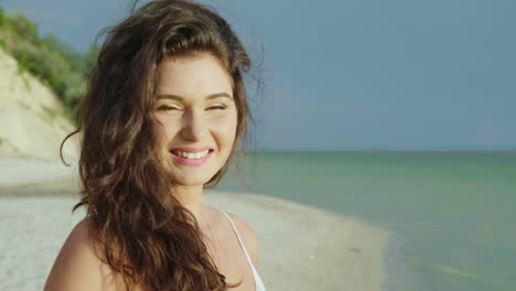 Portrait-Of-A-Young-Woman-On-A-Tropical-Beach-Looks-At-The-Camera-Smiling